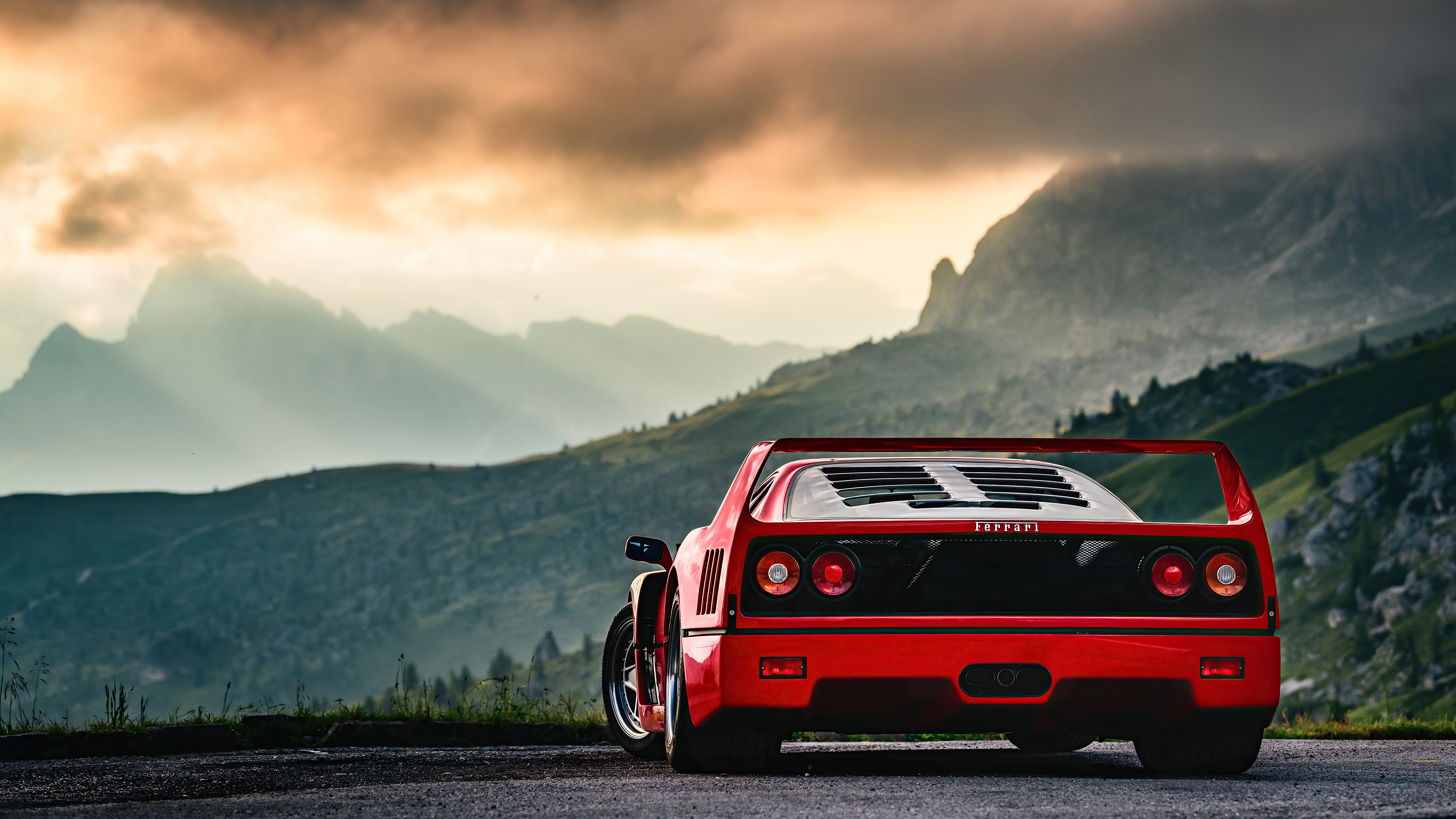 Red Ferrari F40 parked infront of a mountainous area